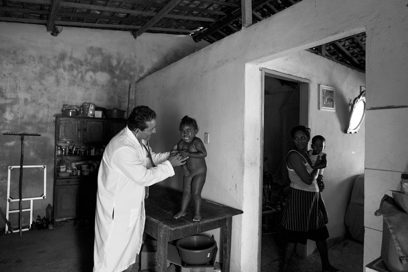 Um médico do programa Mais Médicos cuida de uma criança em sua residência. SUS celebra 35 anos em 2025 e é preciso pensar no seu futuro.