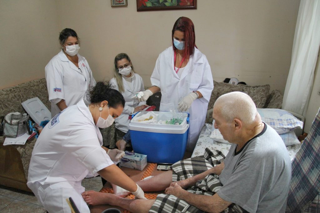 Equipe de saúde da Atenção Primária realiza visita domiciliar para acompanhamento de paciente, reforçando a importância do fortalecimento da atenção básica no SUS.