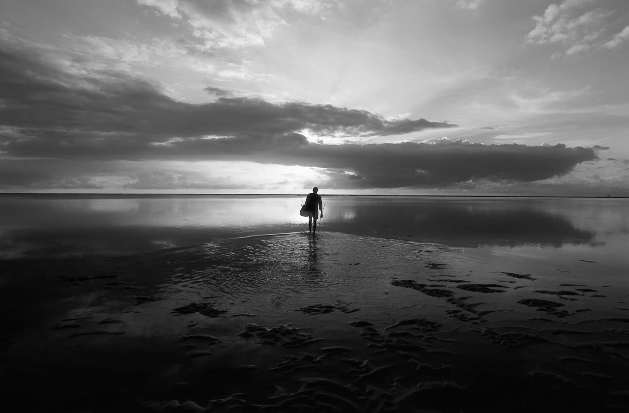 Homem encara o horizonte de frente para o mar. Outra Saúde faz retrospectiva de 2025. 